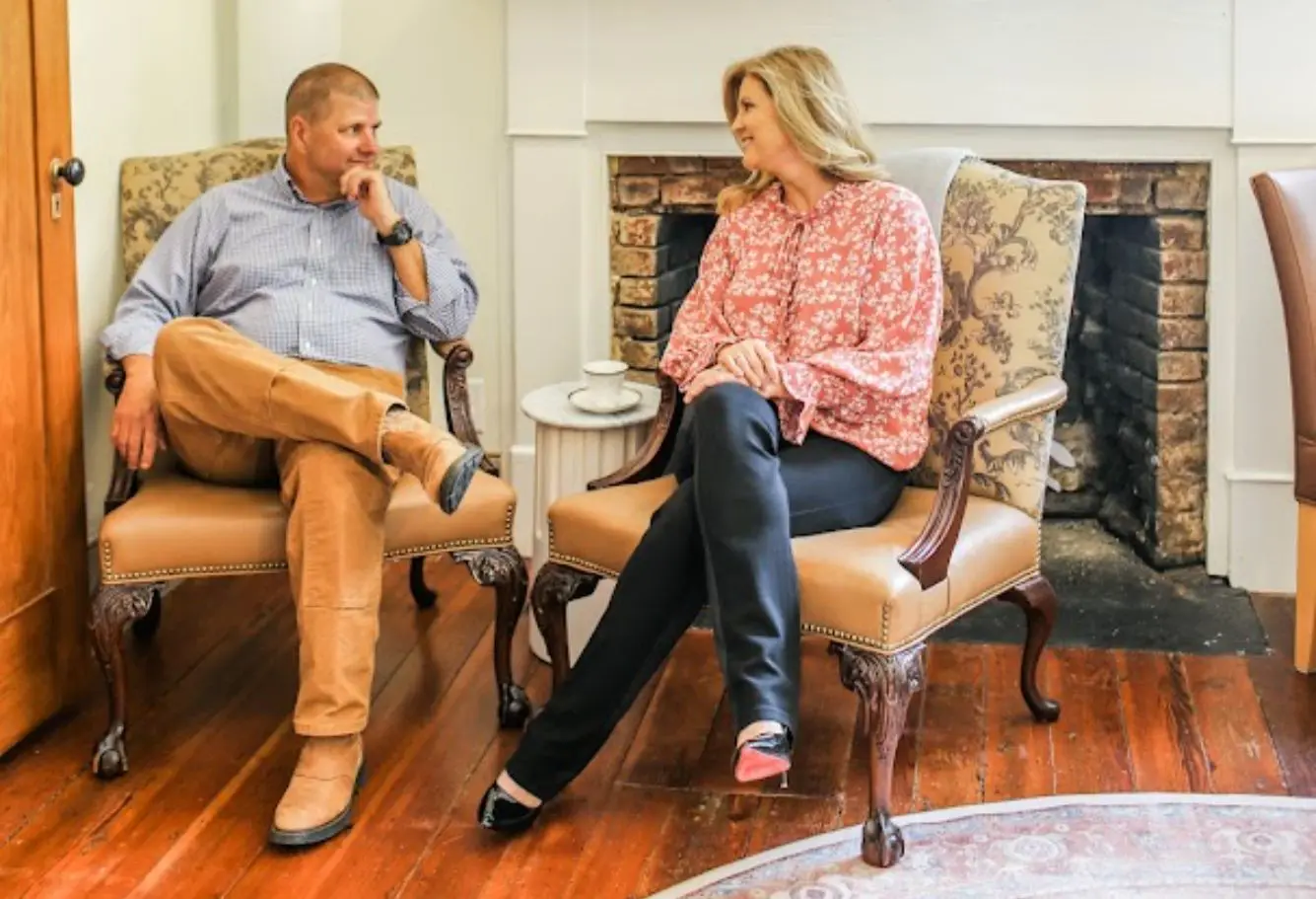 Two people engaged in a thoughtful conversation in a cozy living room.