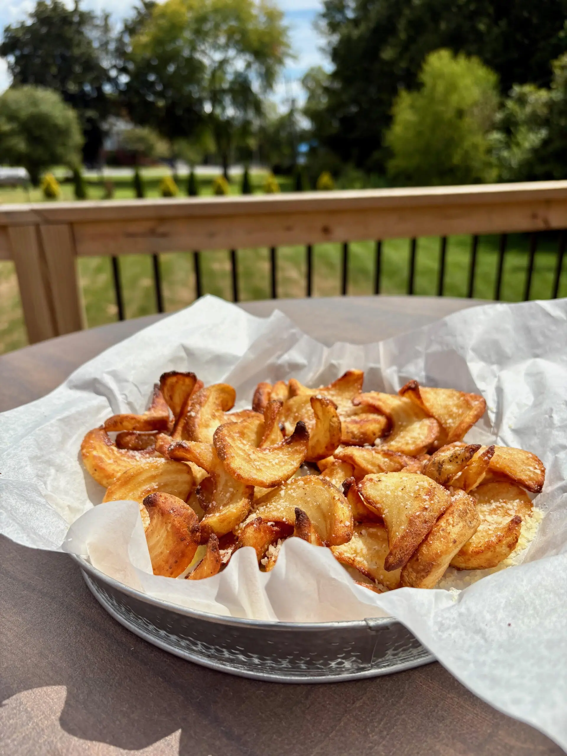 A plate of freshly baked cinnamon rolls on a wooden deck.