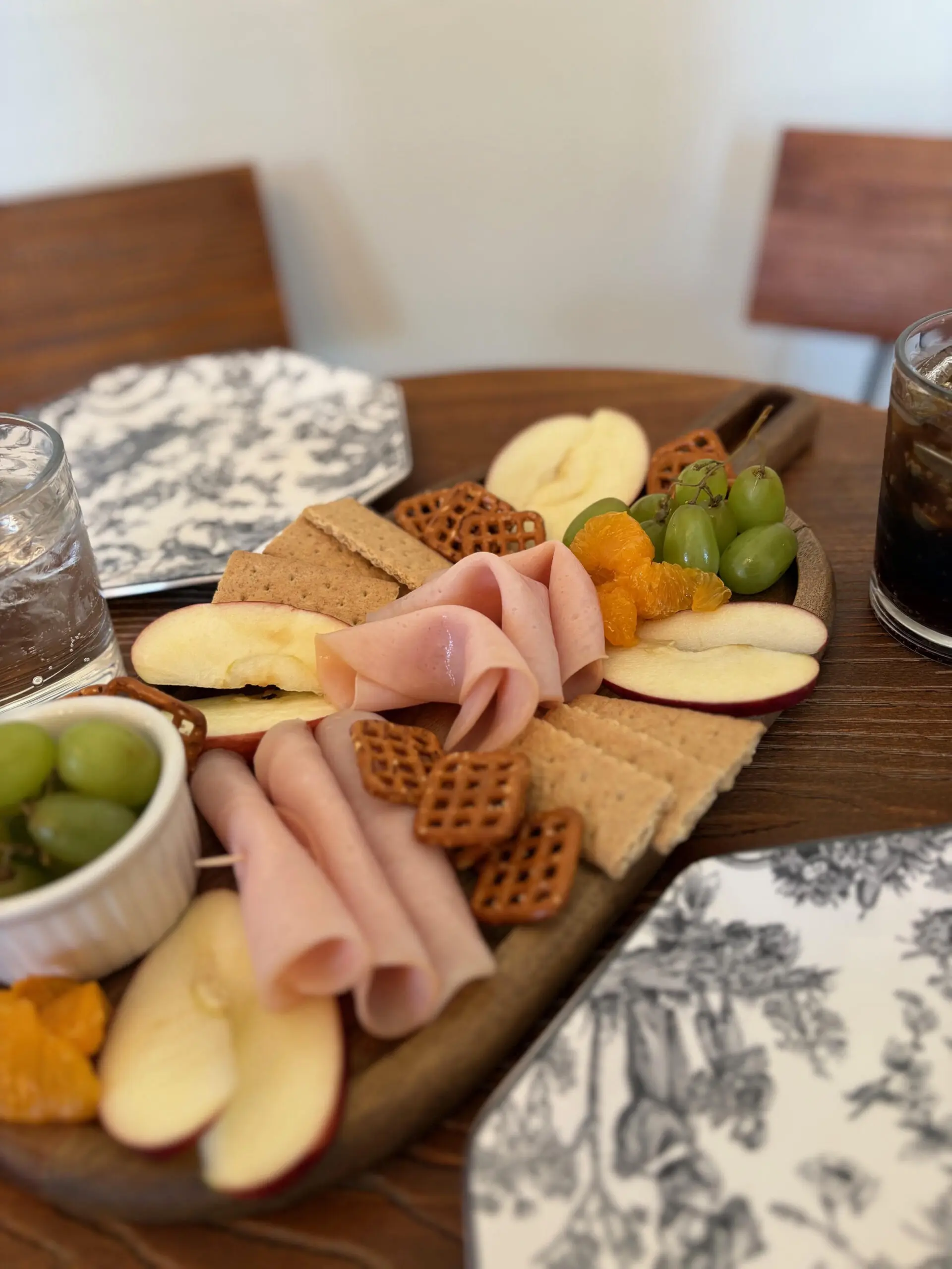 A charcuterie board with meats, cheeses, fruits, and crackers.