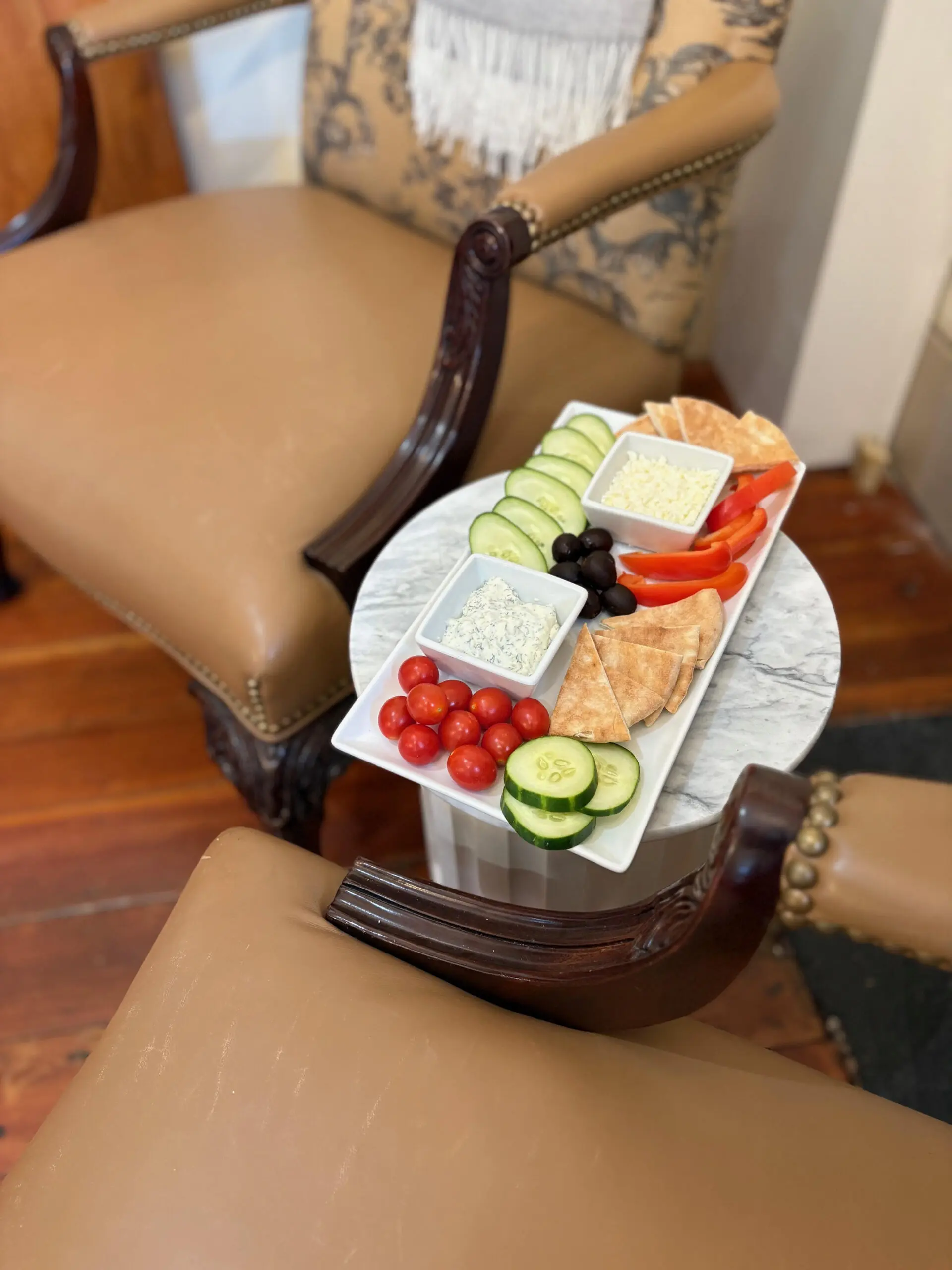A beautifully arranged charcuterie board with various cheeses, meats, and vegetables on a small table.